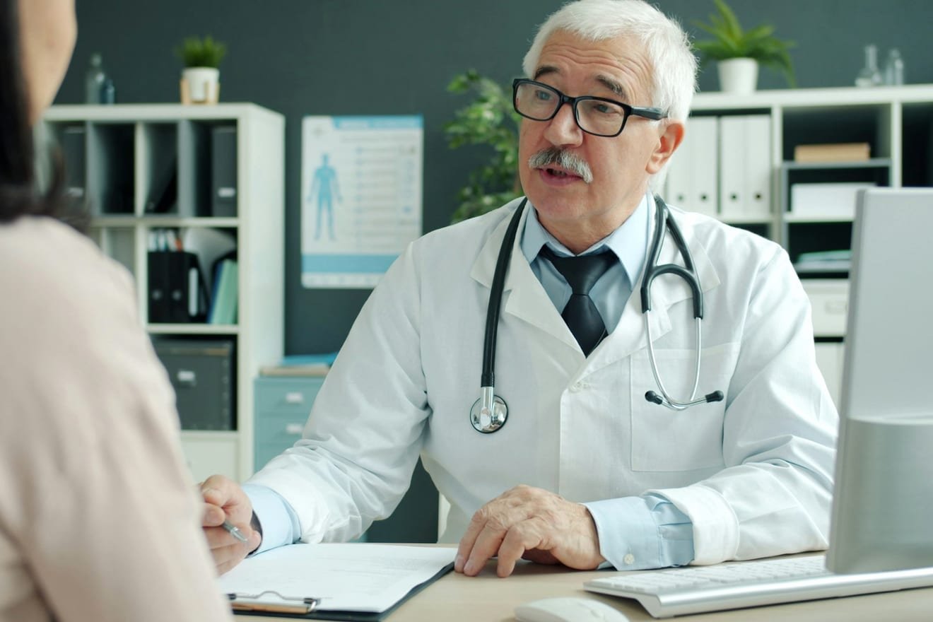 Hausarzt im Gespräch mit einer Patientin in der Praxis